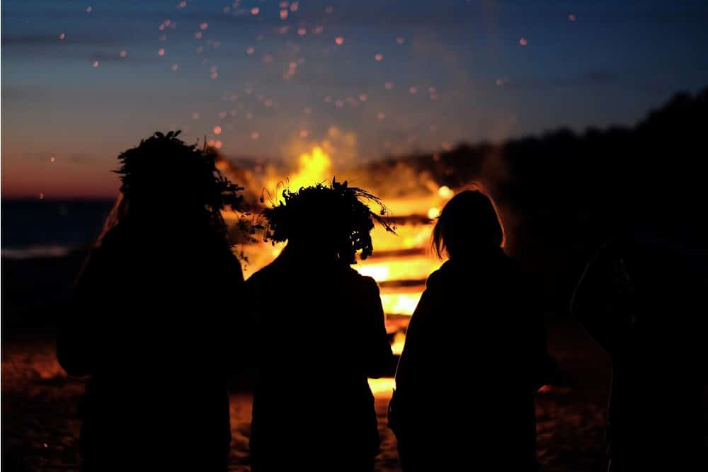 witches at a summer solstice bonfire wearing flower crowns
